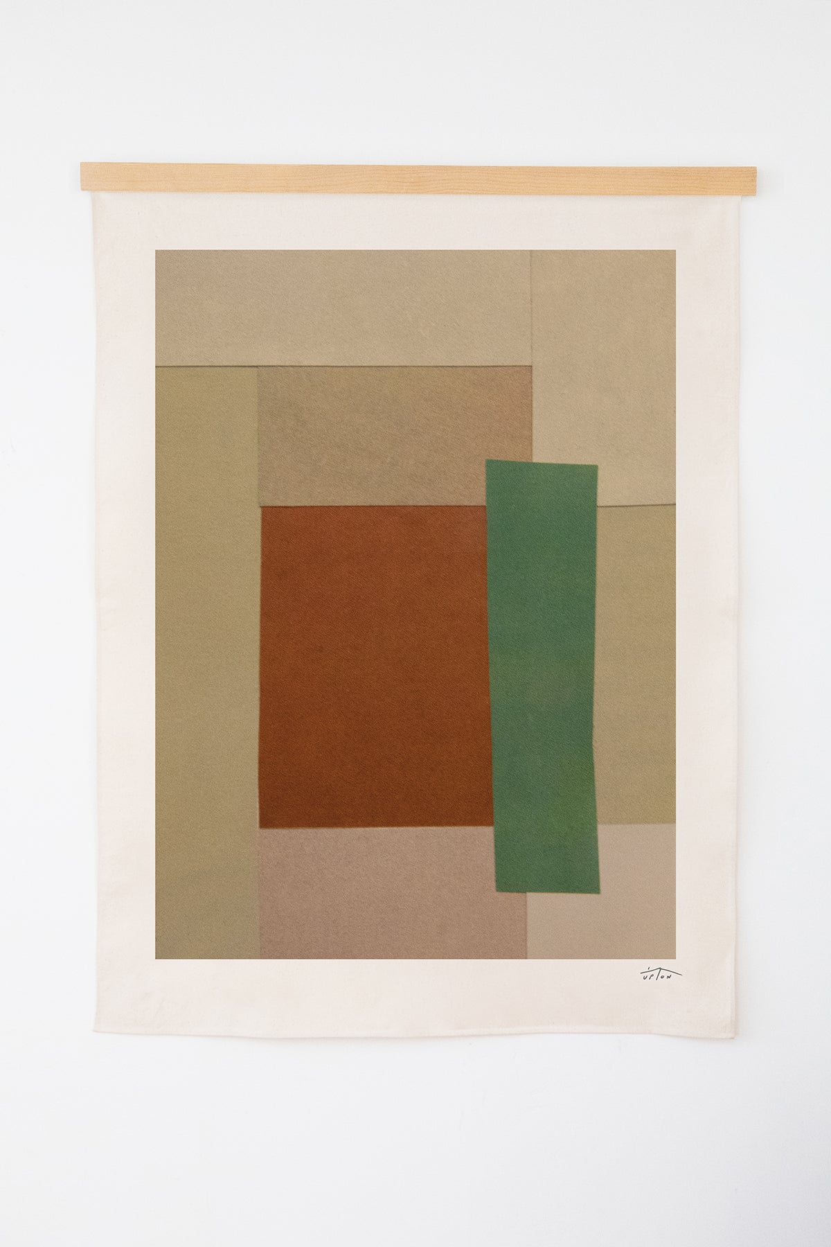 The Cadastral is an original art print on 100% cotton canvas from Michael Upton. Featuring an abstract quilt-like collage design in earth tones and muted neutrals, the Cadastral is a large format modern wall hanging. Shown here with a wooden hanging bar on a white background.