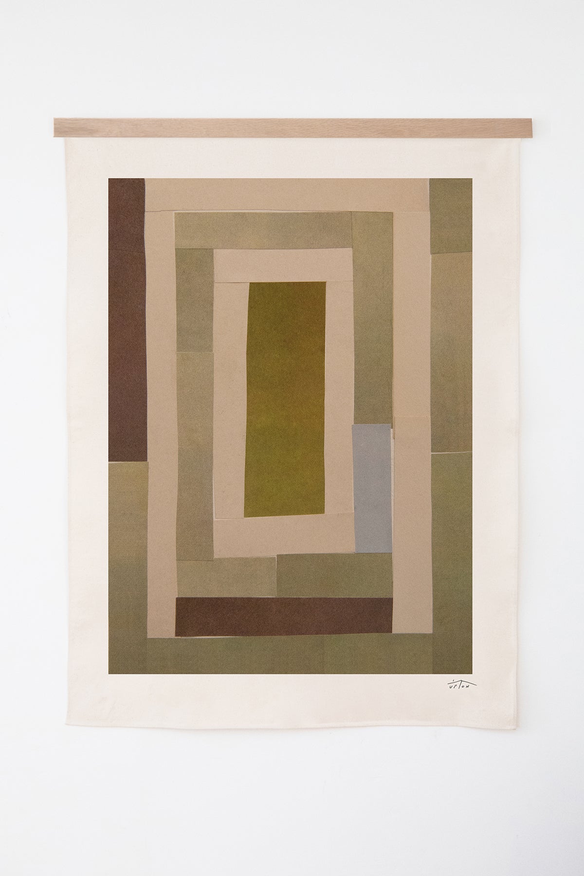 The Illum is an original art print on 100% cotton canvas from Michael Upton. Featuring an abstract quilt-like collage design in muted earth tones, the Illum is a large format modern wall hanging. Shown here with a wood hanging bar on a white background.