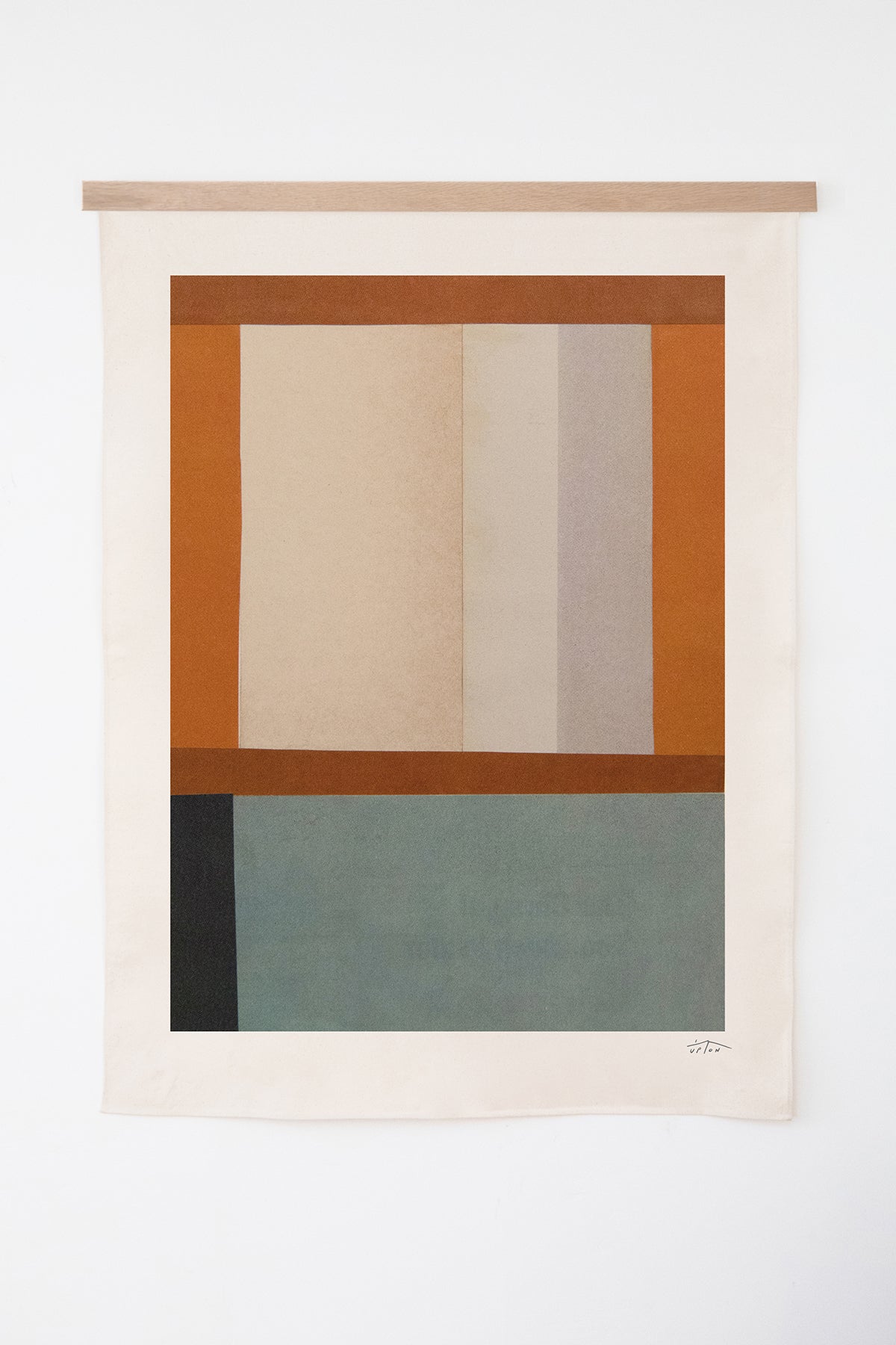 The Vela is an original art print on 100% cotton canvas from Michael Upton. Featuring an abstract quilt-like collage design in rich earth tones, the Vela is a large format modern wall hanging. Shown here with a wood hanging bar on a white background.