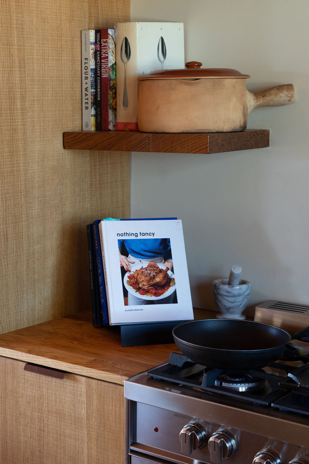 Upton LP Record Stand in black. Modern and minimalist tabletop steel vinyl record holder made for the storage, organization, and display 50 albums. Shown being used as a cookbook holder with an Alison Roman cookbook in a rustic kitchen with ceramics.