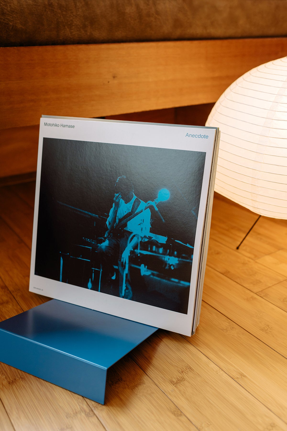 Upton LP Stand in blue. Steel storage and display stand holding a record sleeve in a wooden interior with lamp.