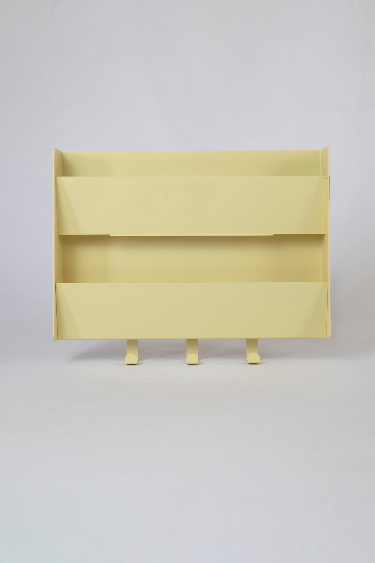 The Upton Mail Organizer in butter. Modern, minimalist, and design-forward wall-mounted mail organizer made of steel with a light yellow powder coat finish. Featuring two slots for mail and three sturdy hooks to hang keys, coats, bags, etc. Shown on a white background.