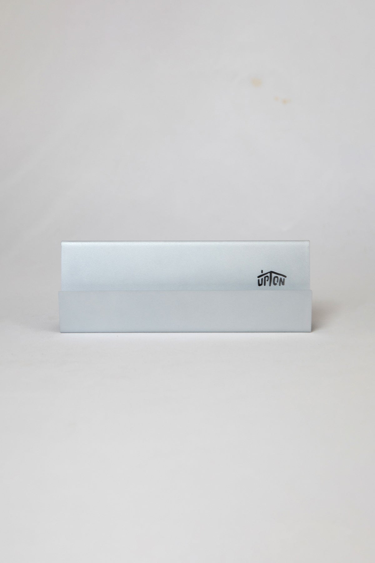 Upton Now Playing Record Stand in matter silver. Modern and minimalist steel display stand made to hold the record sleeve for the vinyl album currently playing on the turntable. Shown on a white background.