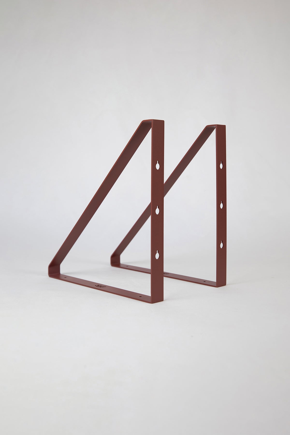 Upton Shelf Bracket Set in rose (red/pink). With a modern, minimalist design and made from powder coated steel, these slim triangle brackets are a unique home storage solution that adds character and color to your home. Shown on a white background.