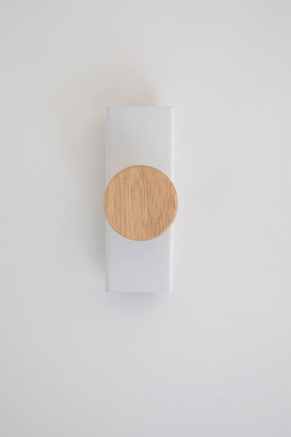 Upton Canal Wall Hook in white. A sculptural decorative steel and wood wall hook with a white color scheme with a unique shape, designed to hang bags, coats, towels, hats, and more. Shown here on a white background.