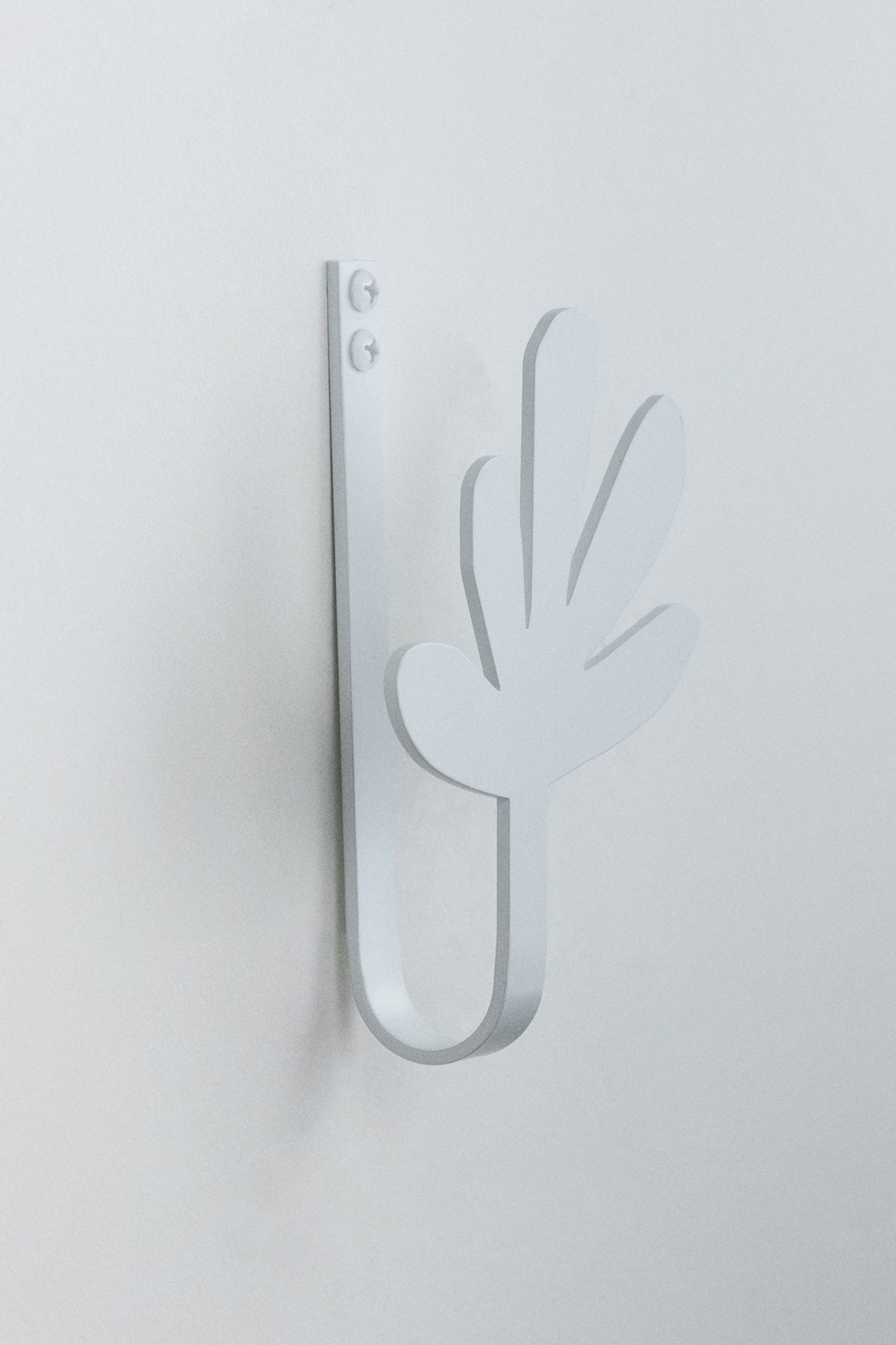 Upton Flora Wall Hook in white. A sculptural decorative steel wall hook with a white color scheme with a unique abstract shape, designed to hang bags, coats, towels, hats, and more. Shown here on a white background.
