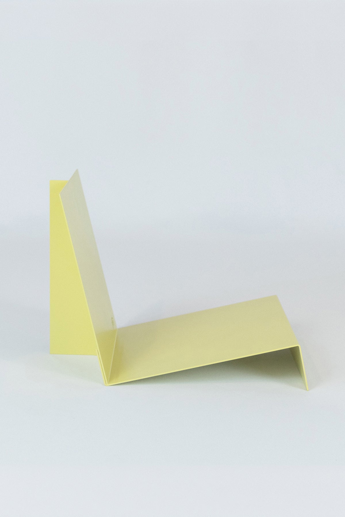 Upton LP Stand in pale yellow. Modern and minimalist tabletop steel vinyl record holder made for storage, organization, and display of 50 albums on a white background.