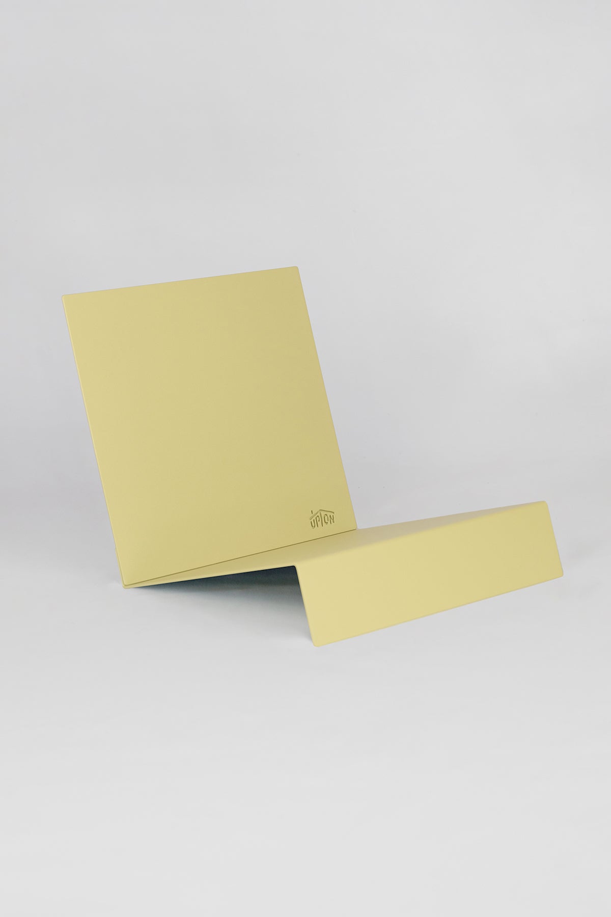 Upton LP Stand in pale yellow. Sculptural steel storage and display stand made to hold records on a white background