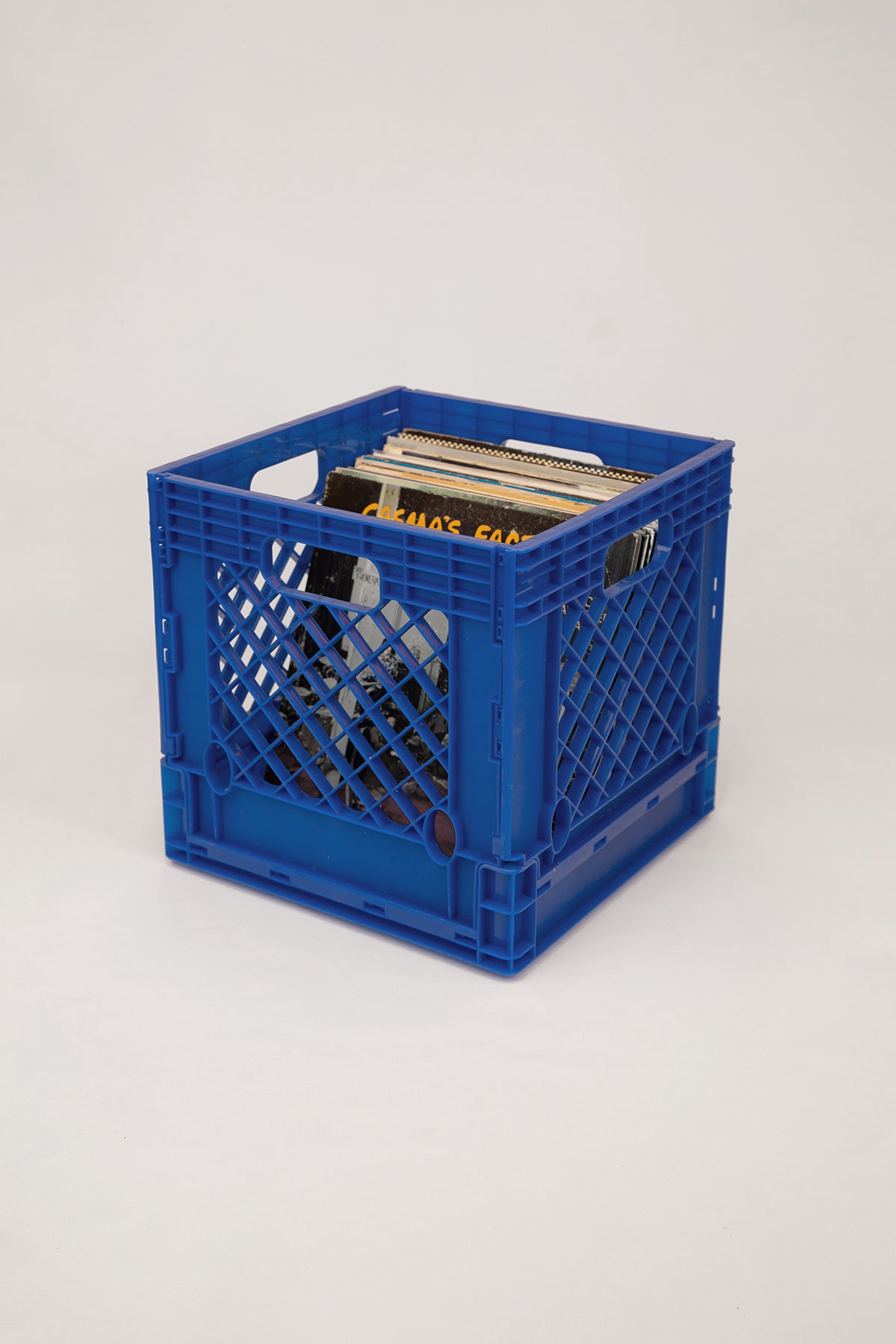 Upton Collapsible Record Crate in royal. Blue milk crate with vintage compact discs on a white background