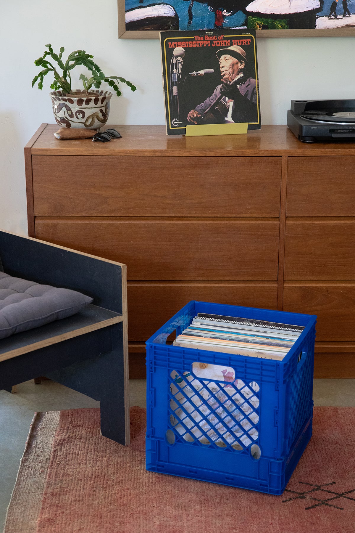 Upton Collapsible Record Crate in royal. Blue crate filled with records on a rug next to a wooden dresser with vinyl records and a plant.