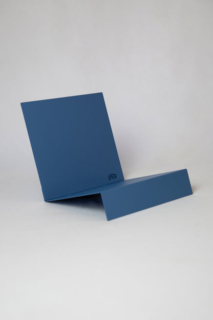Upton LP Record Stand in blue. Modern and minimalist tabletop steel vinyl record holder made for the storage, organization, and display 50 albums. Shown on a white background.