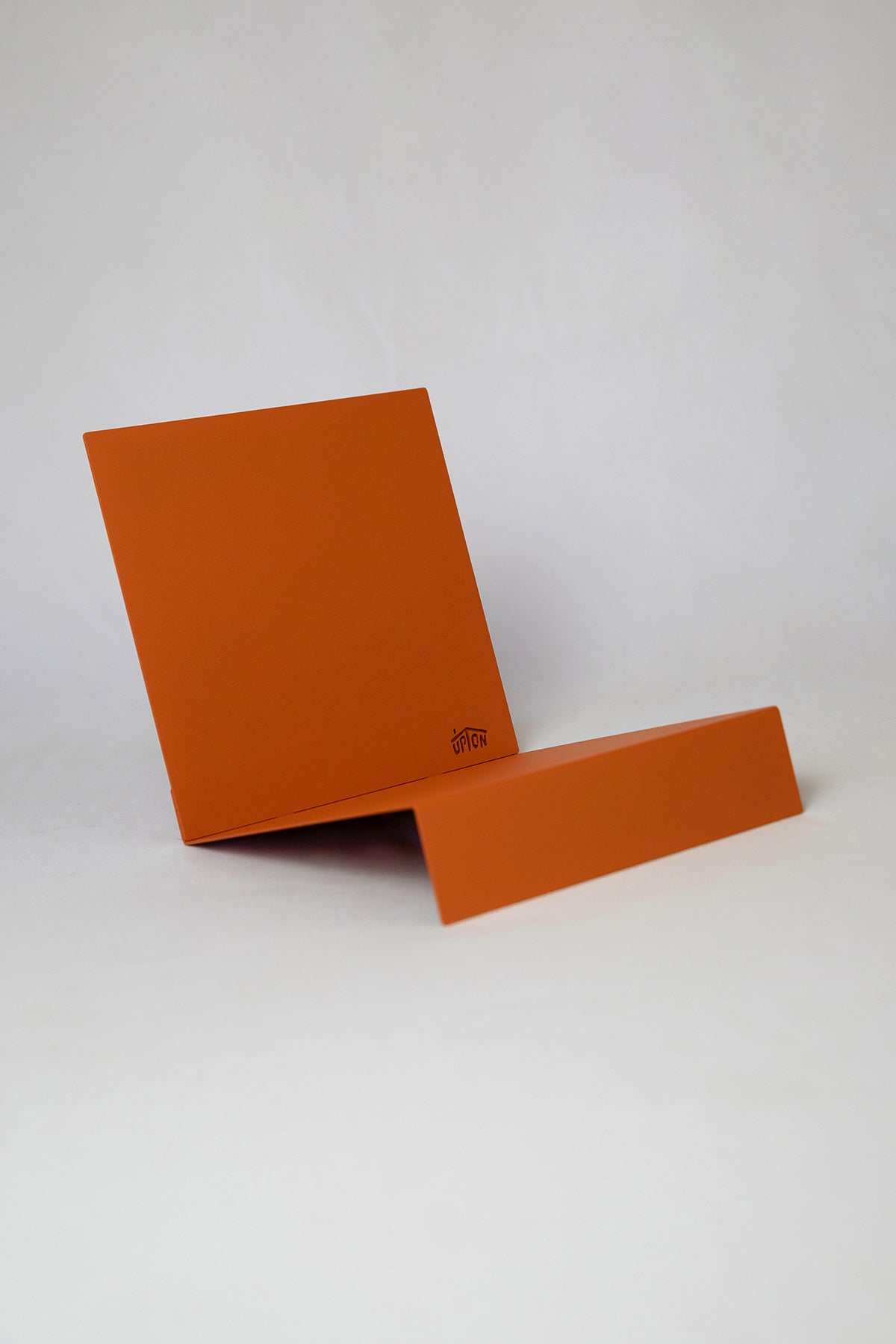 Upton LP Record Stand in burnt orange. Modern and minimalist tabletop steel vinyl record holder made for the storage, organization, and display 50 albums. Shown on a white background.