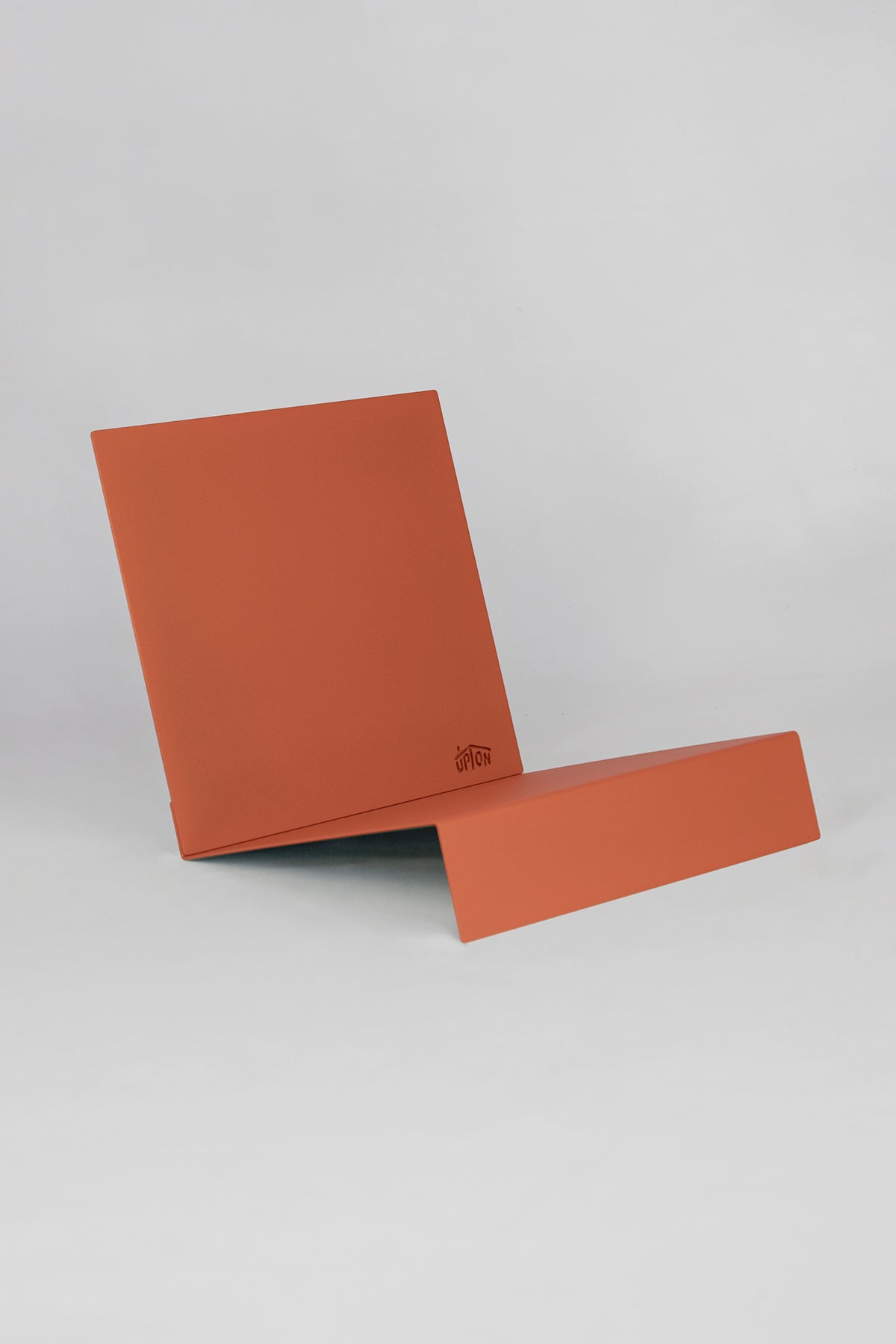 Upton LP Stand in burnt orange. Sculptural steel storage and display stand made to hold records on a white background