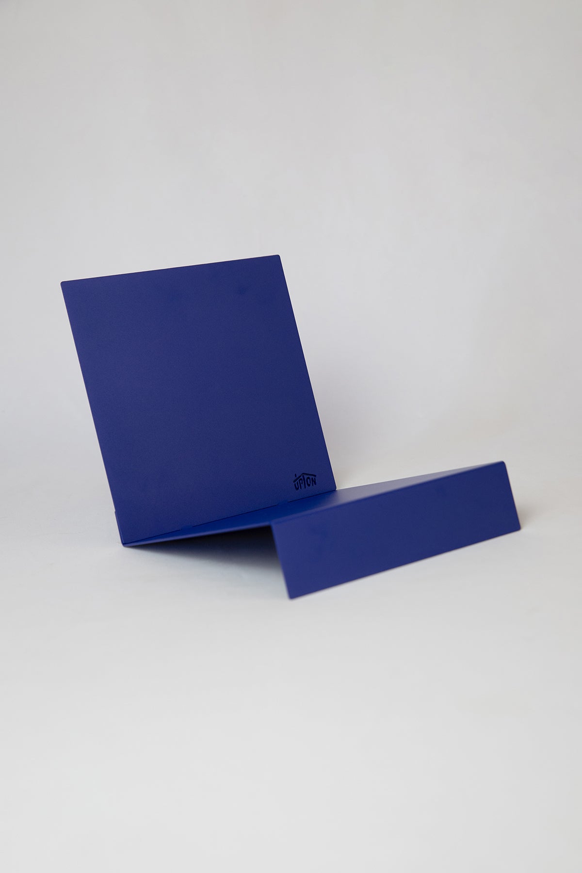 Upton LP Record Stand in cobalt blue. Modern and minimalist tabletop steel vinyl record holder made for the storage, organization, and display 50 albums. Shown here on a white background.