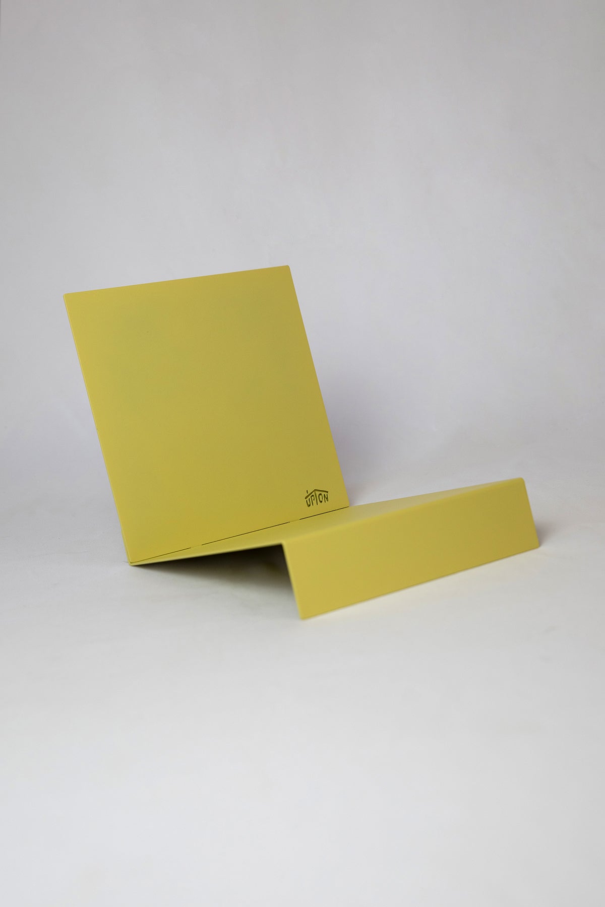 Upton LP Record Stand in pale yellow. Modern and minimalist tabletop steel vinyl record holder made for the storage, organization, and display 50 albums. Shown on a white background.