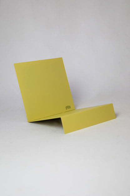 Upton LP Record Stand in pale yellow. Modern and minimalist tabletop steel vinyl record holder made for the storage, organization, and display 50 albums. Shown on a white background.