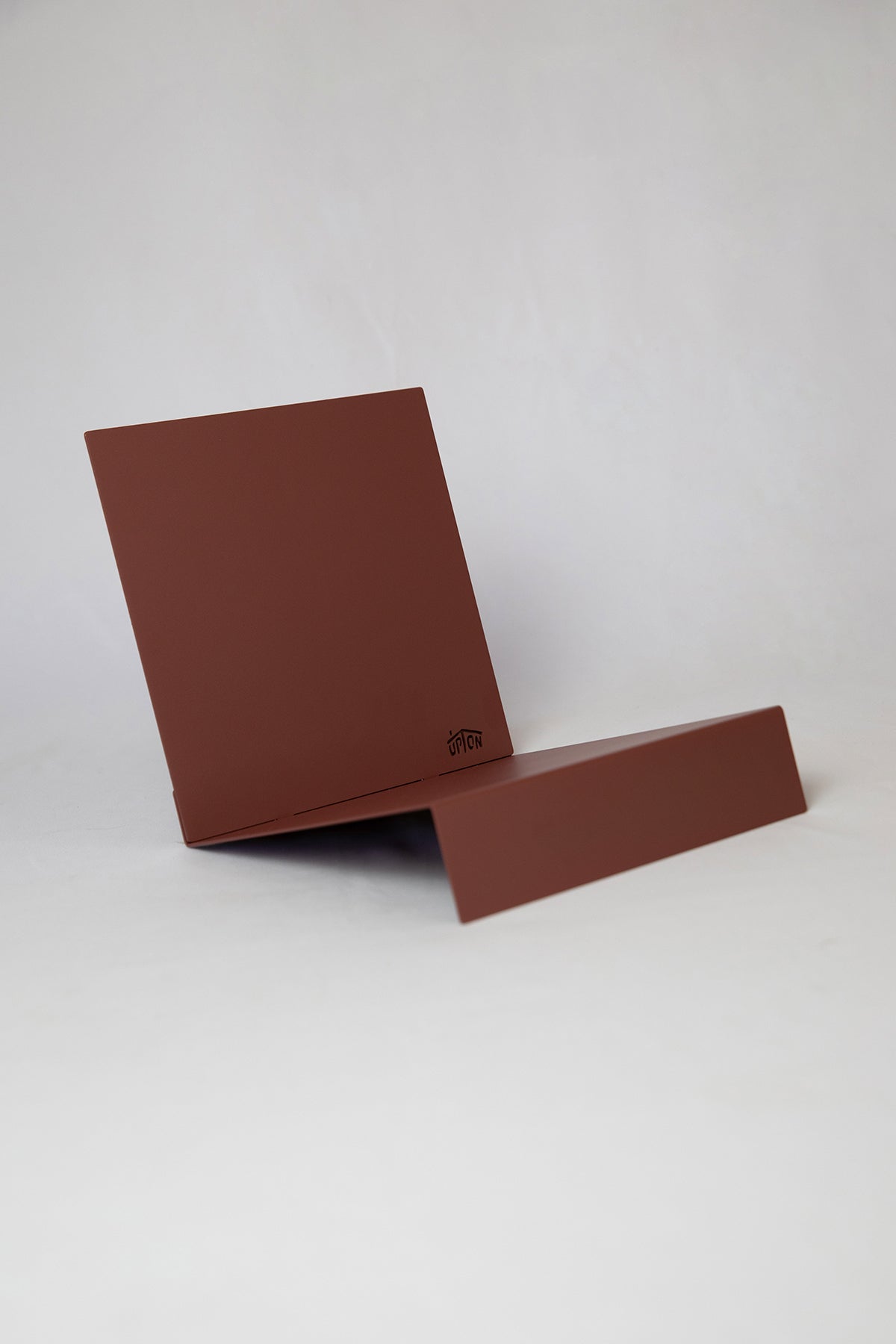 Upton LP Record Stand in rose (red / pink). Modern and minimalist tabletop steel vinyl record holder made for the storage, organization, and display 50 albums. Shown on a white background.