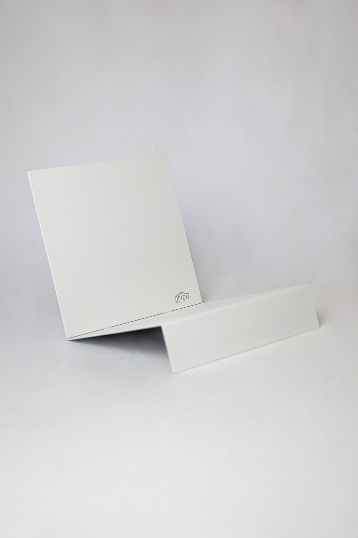 Upton LP Record Stand in white. Modern and minimalist tabletop steel vinyl record holder made for the storage, organization, and display 50 albums. Shown on a white background.