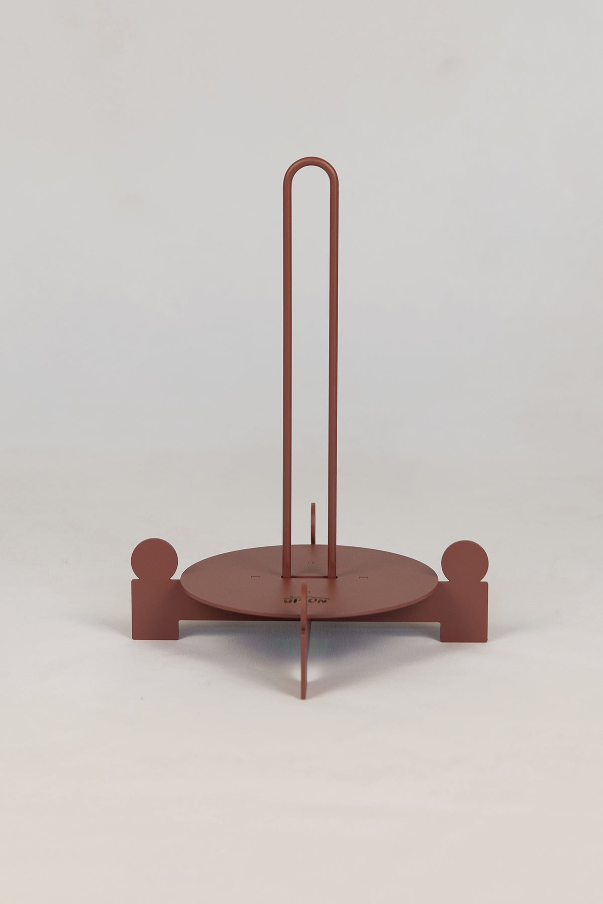 Upton Bal Paper Towel Holder in rose. Sculptural metal freestanding paper towel holder in a rose (red/pink) color with circular base and vertical rod. Shown here on a white background.