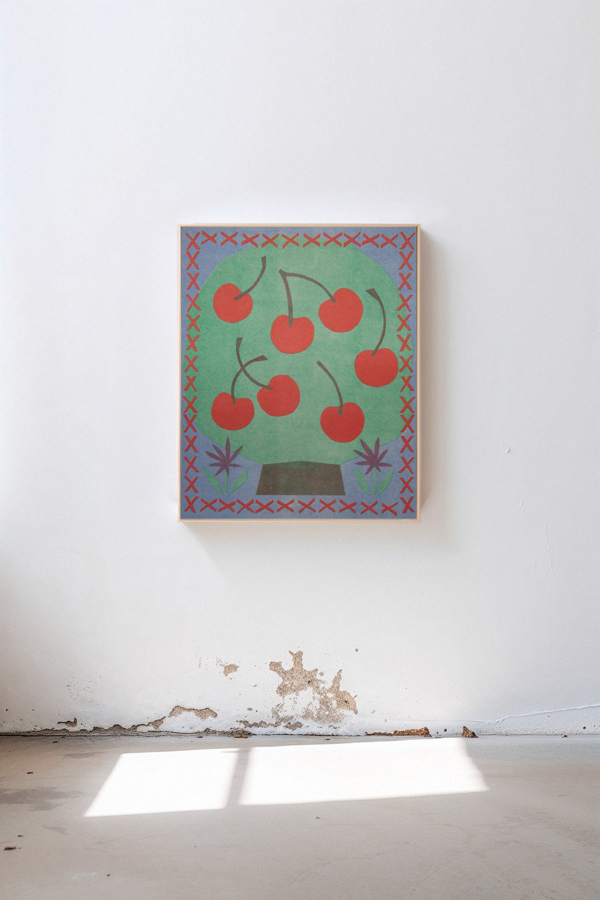 Cherry Tree by Sunroom Studios x Upton, a custom framed art print on 100% cotton canvas. Large cut paper collage of a stylized cherry tree in cheerful reds, greens, and blues, shown in a gallery setting with concrete floors and natural light.