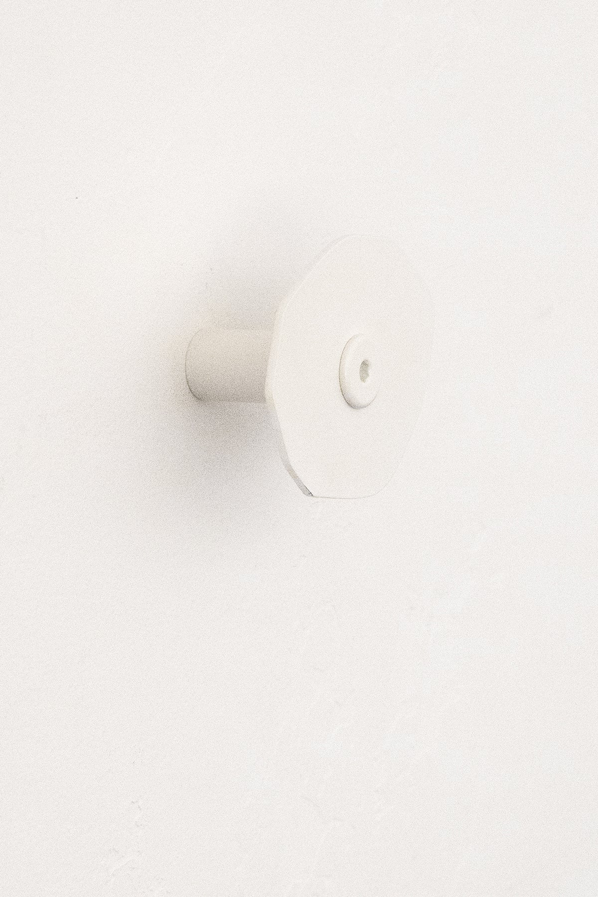 Upton Corte Wall Hook in white. Sculptural steel wall hook made to hang bags, jackets, and more on a white background.