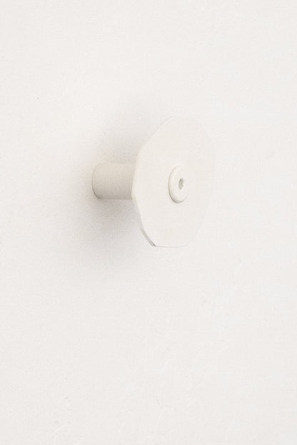 Upton Corte Wall Hook in white. Sculptural steel wall hook made to hang bags, jackets, and more on a white background.