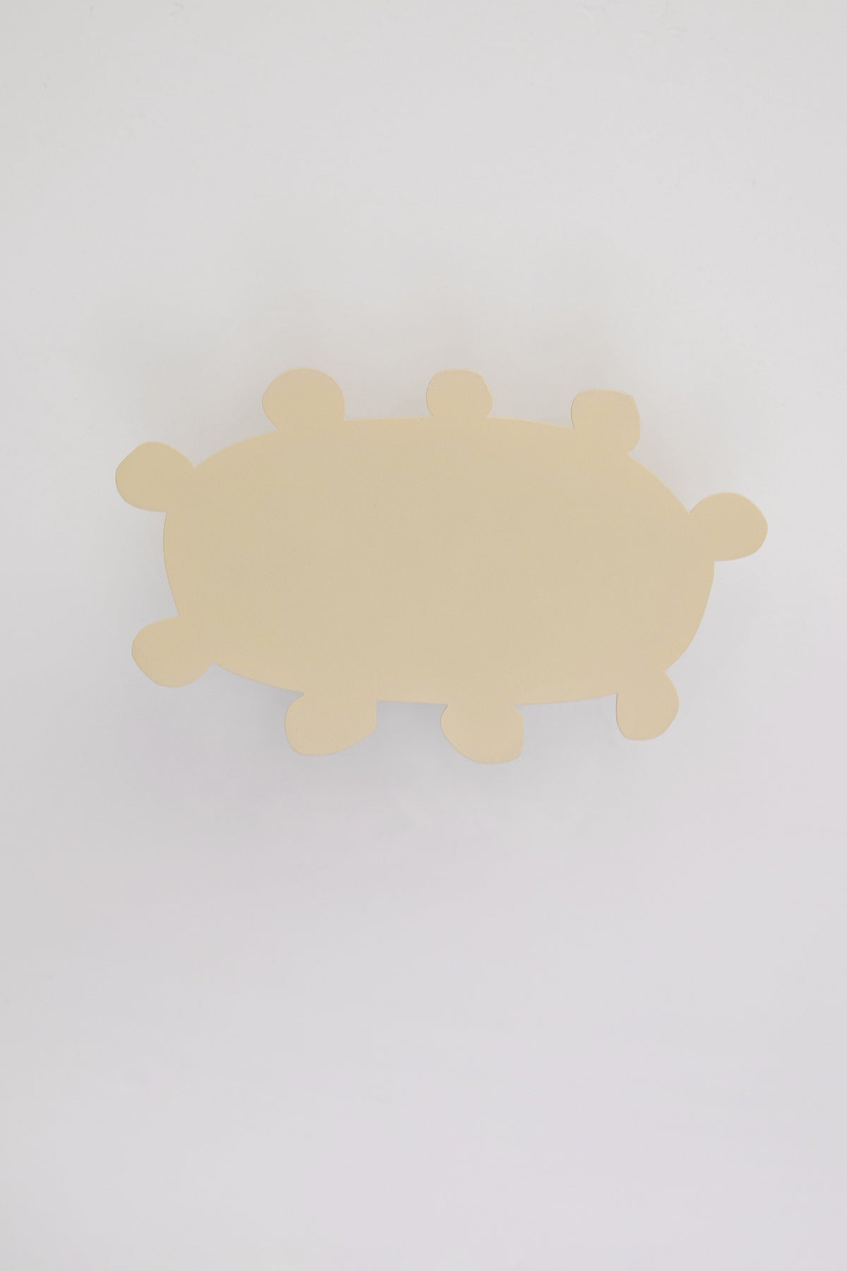 Upton Soli Wall Hook in butter. A sculptural decorative steel wall hook with a butter yellow color scheme with a unique abstract shape, designed to hang bags, coats, towels, hats, and more. Shown here on a white background.